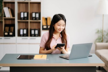 Asyalı bir kadın dizüstü bilgisayar kullanarak masada oturuyor. Teknoloji ile Maliye ve Pazarlama Ofisinde Yönlendirme