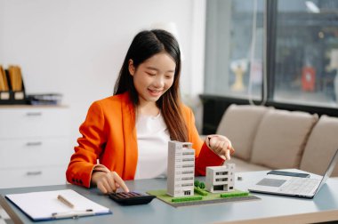 Emlak komisyoncusu, emlak kredisi teklifiyle ilgili sözleşme imzalama anlaşmasını, ev modelini sunar ve müşteriye danışmanlık yapar.