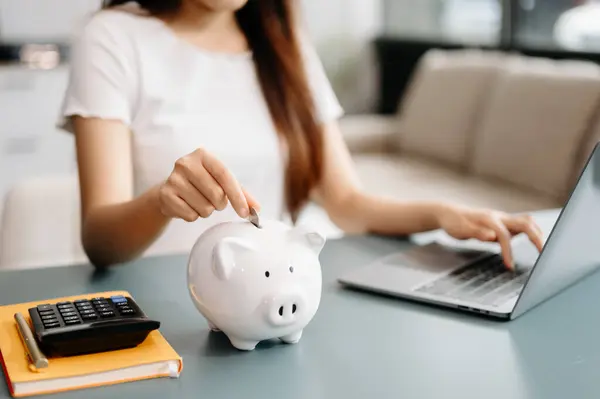 Asian Women are putting coins in a piggy bank for a business that grows for profit and saving money for the future. planning for retirement concept
