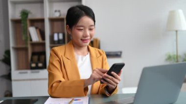 Asyalı kadın iş yerinde otururken telefonu kullanıyor.. 
