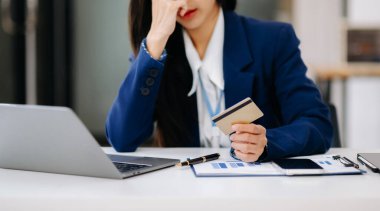 Ofiste çalışırken dizüstü bilgisayar kullanan ve kredi kartı tutan girişimci bir kadın. 