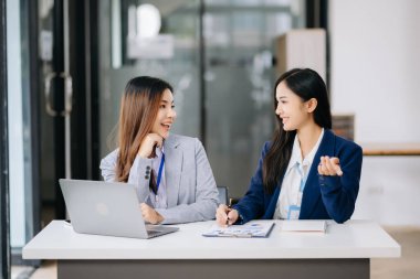 Ofisteki dizüstü bilgisayarla proje üzerinde çalışan iki çekici Asyalı kadın.. 