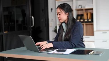 Asyalı güzel kadın çalıştığı yerde dizüstü bilgisayar kullanıyor.. 