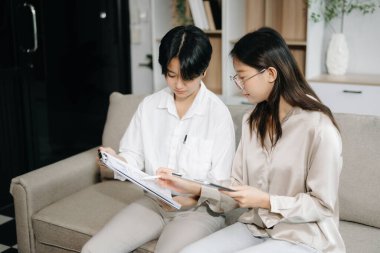 Ofisteki kanepede konuşan ve dijital tablet kullanan iki genç iş adamı.