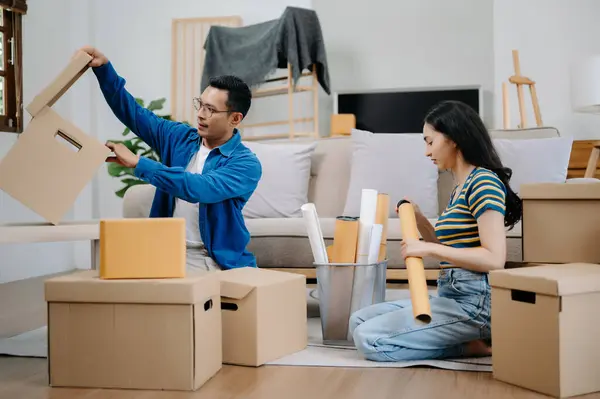 Young couple with big boxes moving into a new house. Asian man and woman helping to lift boxes on sofa for the new home, Moving house concept