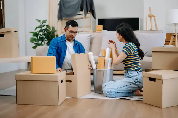 Young couple with big boxes moving into a new house. Asian man and woman helping to lift boxes on sofa for the new home, Moving house concept