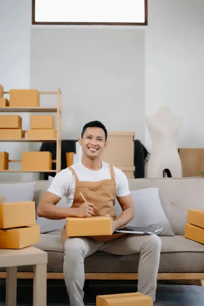 Young man running online store Startup small business SME, using digital tablet taking receive and checking online purchase shopping order in office
