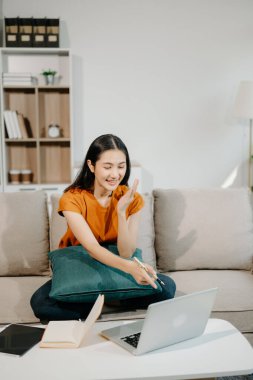 Kanepede oturan Asyalı kadın dizüstü bilgisayar kullanıyor, Finans ve Teknoloji ile Pazarlama