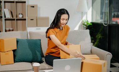 Küçük işletme girişimcisi KOBİ 'li serbest kadın, ev bilgisayarında, pazarlamada, ambalajda, dağıtımda, e-ticaret konseptinde çalışıyor.