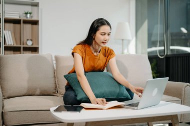 Kanepede oturan Asyalı kadın dizüstü bilgisayar kullanıyor, Finans ve Teknoloji ile Pazarlama