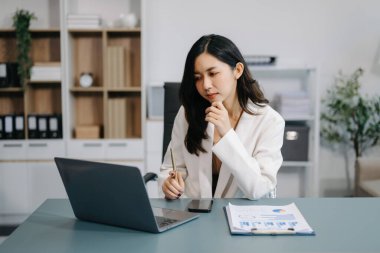 Genç ve güzel bir kadın çalışırken dizüstü bilgisayar kullanıyor. Modern ofiste işe odaklanmış.