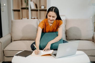 Kanepede oturan Asyalı kadın dizüstü bilgisayar kullanıyor, Finans ve Teknoloji ile Pazarlama