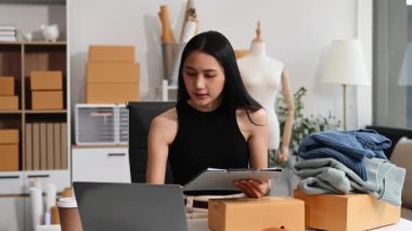  Moda tasarımcısının masasında dizüstü bilgisayar kullanan Asyalı genç bir kadın. 