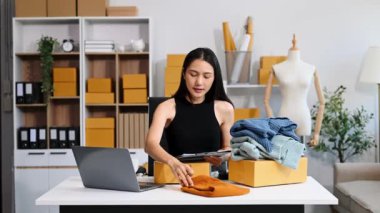  Moda tasarımcısının masasında dizüstü bilgisayar kullanan Asyalı genç bir kadın. 
