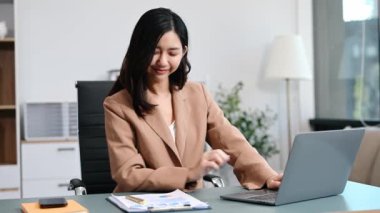 Ofiste belgelerle çalışan Asyalı iş kadını ve dizüstü bilgisayar. 