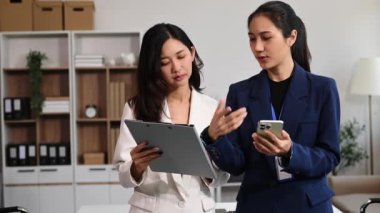 Modern ofiste çalışan başarılı iş kadınlarının portresi, akıllı telefon kullanıyor. 