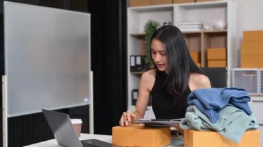  Moda tasarımcısının masasında dizüstü bilgisayar kullanan Asyalı genç bir kadın. 