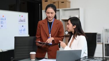 Modern ofiste birlikte çalışan başarılı iş kadınlarının portresi, dizüstü bilgisayar ve dijital tablet kullanarak 