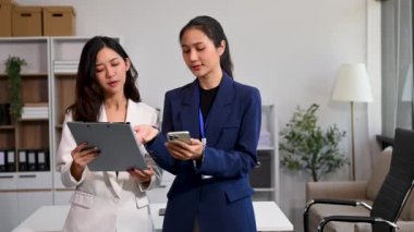 Modern ofiste çalışan başarılı iş kadınlarının portresi, akıllı telefon kullanıyor. 