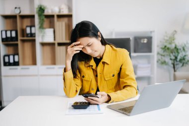 Genç ve güzel bir kadın ofiste geç saatlere kadar çalışıyor. Akıllı telefona bakarken iş yerinde eğilen üzgün bir iş kadını.