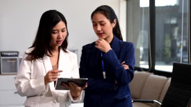 Modern ofiste dijital tablet kullanarak birlikte çalışan başarılı iş kadınlarının portresi 