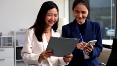 Modern ofiste çalışan başarılı iş kadınlarının portresi, akıllı telefon kullanıyor. 