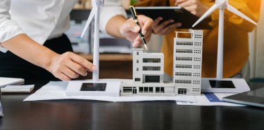 Çalışan iş adamları ve yeşil yenilenebilir enerji arayüzü ve dijital tablet kullanıyorlar. Yenilenebilir kaynaklara dayalı sürdürülebilirlik işi kavramı 
