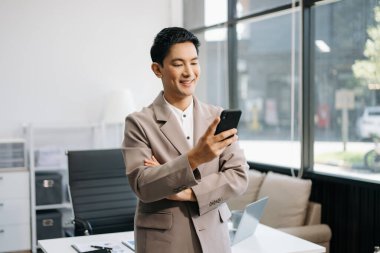 Kendine güvenen iş uzmanı yaratıcı ofiste akıllı telefon tutuyor..