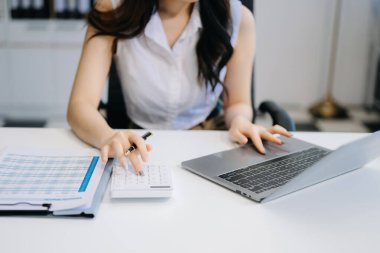 Serbest çalışan bir kadın dizüstü bilgisayarda çalışıyor. Muhasebe analizi raporları, emlak yatırım verileri, ofiste finans.