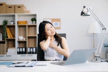 Ofiste uzun bir gün geçirdikten sonra boynu ağrıyan Asyalı genç işkadını ofis çalışanı. ofis sendromu kavramı