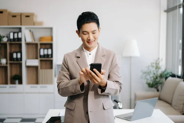 Confident business expert holding smartphone in creative office.