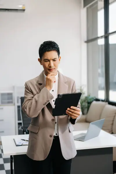 Confident business expert holding digital tablet in creative office.