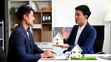Emlak komisyoncusu, emlak kredisi teklifiyle ilgili sözleşme imzalama anlaşmasını, ev modelini sunar ve müşteriye danışmanlık yapar.
