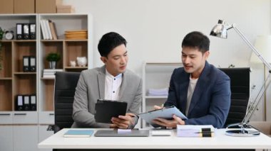 İşadamları ofiste dijital tablet kullanarak iş planlarını tartışıyor.