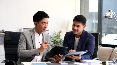 İşadamları ofiste dijital tablet kullanarak iş planlarını tartışıyor.