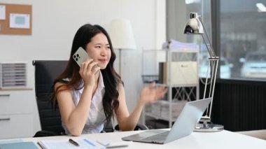 Başarılı Asyalı İş kadını Laptop 'ta Finans Analizi ve modern ofis masasında akıllı telefondan konuşma. vergi, rapor, muhasebe, istatistik ve analitik araştırma kavramı