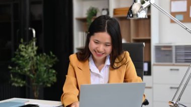 Ofiste çalışmak için dizüstü bilgisayar kullanan çekici bir iş kadını.  