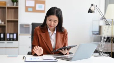 Ofiste çalışan Asyalı iş kadını dijital tablet ve dizüstü bilgisayar kullanıyor. 