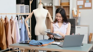  Moda tasarımcısının masasındaki Asyalı genç kadın stüdyoda çalışıyor.