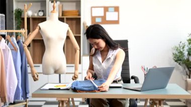  Moda tasarımcısının masasındaki Asyalı genç kadın stüdyoda çalışıyor.