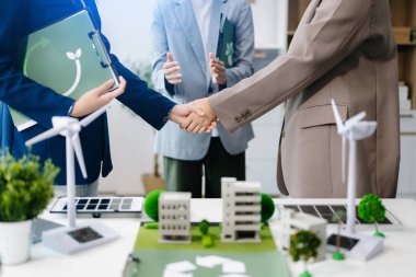 İş adamları toplantı odasında geri dönüşüm sembolü üzerinde el sıkışıyor. Yeşil iş şirketi ve Güneş Enerjisi Çevre Kenti Kavramı