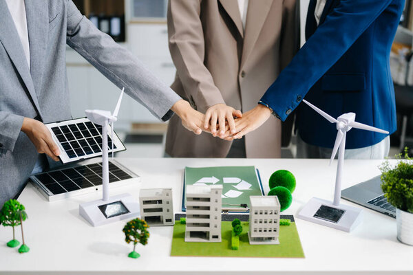 Деловая команда складывает руки на символ вторичной переработки в конференц-зале. Компания зеленого бизнеса и город солнечной энергетики