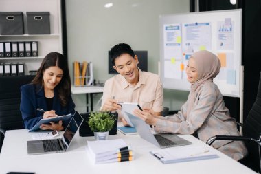 İş ortakları toplantıda belge ve fikirleri tartışıyor, yeni başlangıç projesiyle çalışıyorlar.
