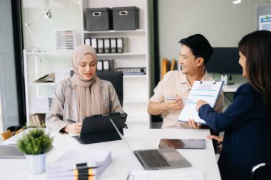 İş ortakları toplantıda belge ve fikirleri tartışıyor, yeni başlangıç projesiyle çalışıyorlar.