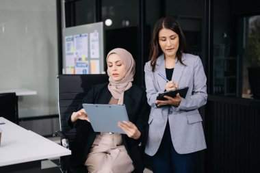 İki kadın işçi konferans odasında ofiste yeni başlatılan projeyi tartışıyor.