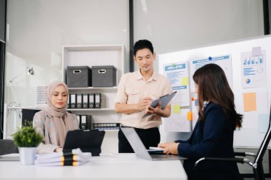 İş ortakları toplantıda belge ve fikirleri tartışıyor, yeni başlangıç projesiyle çalışıyorlar.