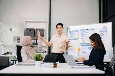 İş ortakları toplantıda belge ve fikirleri tartışıyor, yeni başlangıç projesiyle çalışıyorlar.