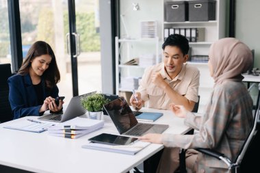 İş ortakları toplantıda belge ve fikirleri tartışıyor, yeni başlangıç projesiyle çalışıyorlar.