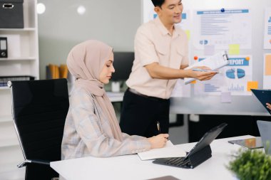 Modern ofis binasında iş planlarını tartışan bir grup genç Asyalı iş adamı
