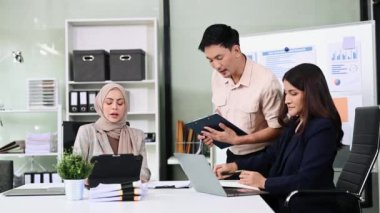 Bir grup genç Asyalı iş adamı bilgisayar ve dijital tablet kullanarak yaratıcı ofiste modern girişimin iş planını tartışıyor. 